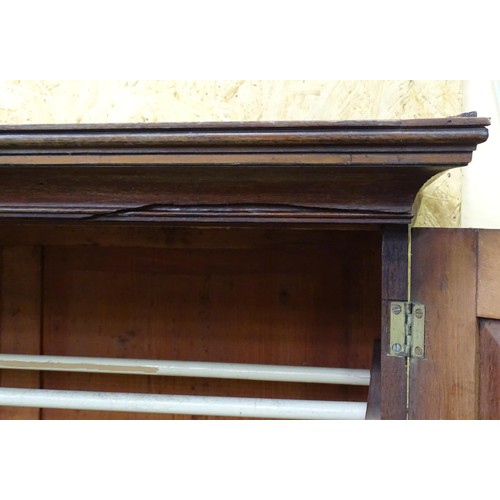 338 - An early 19thC mahogany linen press, having a moulded cornice above two panelled doors and the base ... 