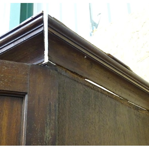 338 - An early 19thC mahogany linen press, having a moulded cornice above two panelled doors and the base ... 