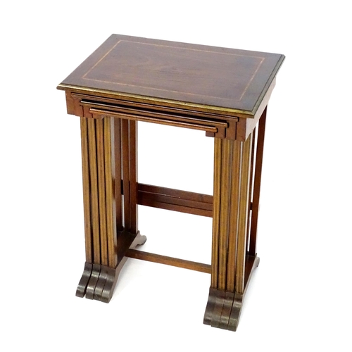 976 - A nest of four early 20thC mahogany tables with satinwood crossbanding and gilt painted moulded surr... 