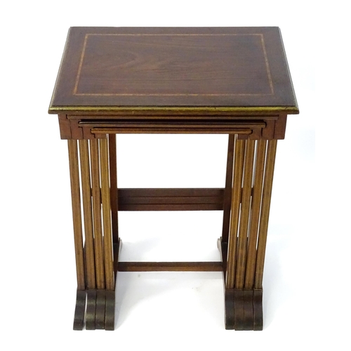 976 - A nest of four early 20thC mahogany tables with satinwood crossbanding and gilt painted moulded surr... 