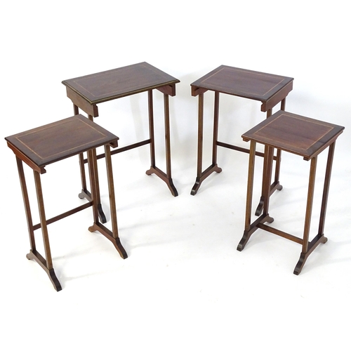 976 - A nest of four early 20thC mahogany tables with satinwood crossbanding and gilt painted moulded surr... 