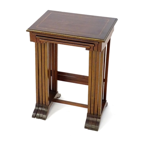 976 - A nest of four early 20thC mahogany tables with satinwood crossbanding and gilt painted moulded surr... 