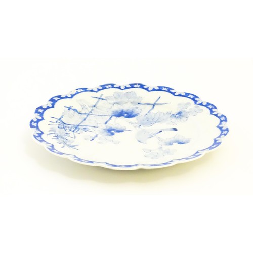 4 - A Japanese blue and white plate with scalloped edge, decorated with a bird perched on a branch with ... 