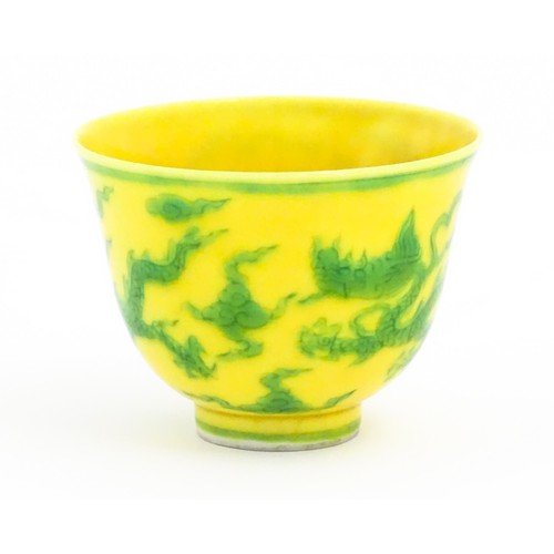 21 - A Chinese wine cup the yellow ground decorated with green dragons and stylised clouds. Character mar... 