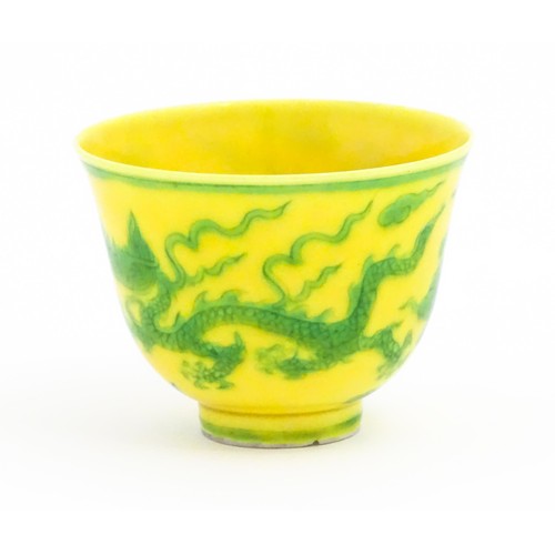21 - A Chinese wine cup the yellow ground decorated with green dragons and stylised clouds. Character mar... 