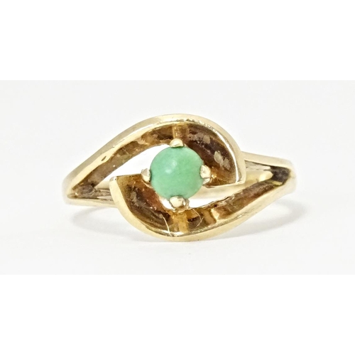 668 - A 9ct gold ring set with central green stone cabochon in an open setting. Ring size approx. O