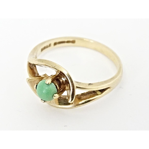 668 - A 9ct gold ring set with central green stone cabochon in an open setting. Ring size approx. O