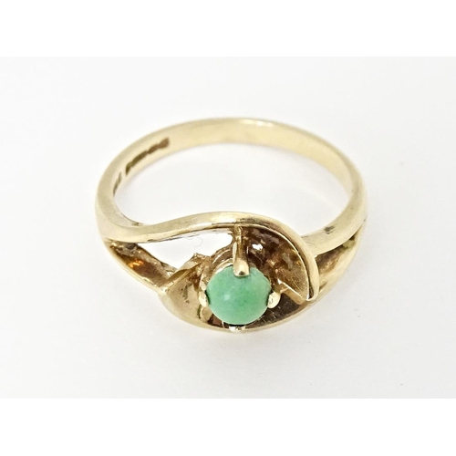 668 - A 9ct gold ring set with central green stone cabochon in an open setting. Ring size approx. O