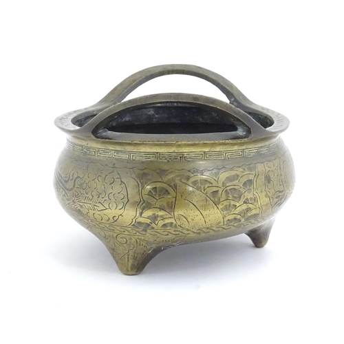 1120 - A Chinese cast twin handled three footed censer with incised dragon and phoenix decoration and bande... 