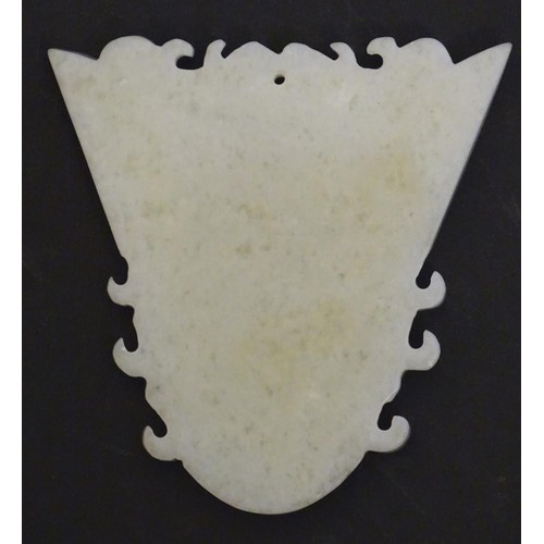 1130 - An Oriental carved hardstone pendant formed as a decorative mask. Approx. 3