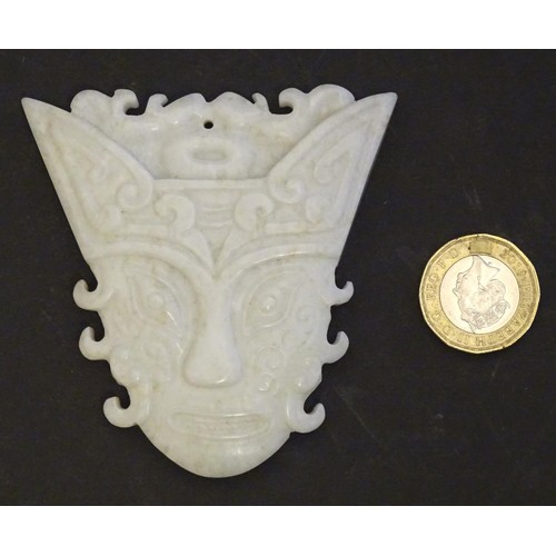 1130 - An Oriental carved hardstone pendant formed as a decorative mask. Approx. 3