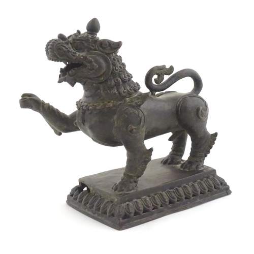 1141 - An Oriental cast temple lion with scrolled tail on a pierced rectangular base. Approx. 7 1/2