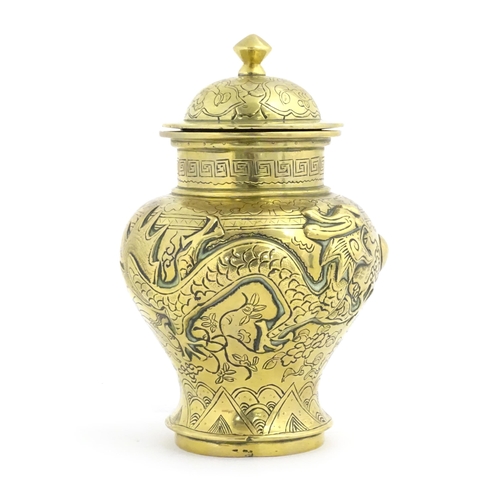 1146 - A Chinese cast brass vase and cover of baluster form with relief decoration depicting dragons and a ... 