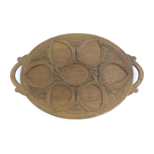 1162 - A carved wooden tray of oval form with scrolled handles, carved foliate decoration and seven section... 