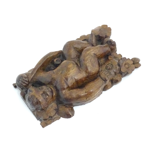 1166 - An early 19thC walnut carving depicting a cherub / putto amongst flowers. Approx. 6 3/4