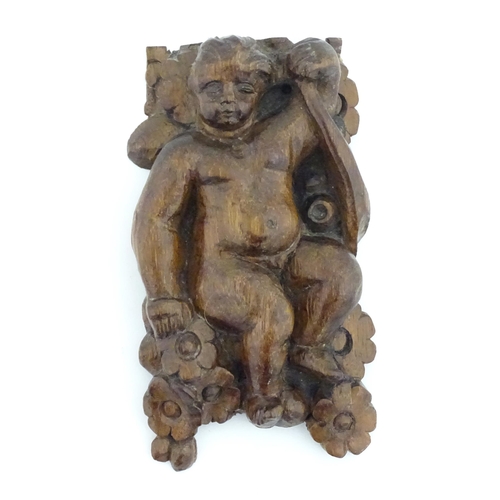 1166 - An early 19thC walnut carving depicting a cherub / putto amongst flowers. Approx. 6 3/4