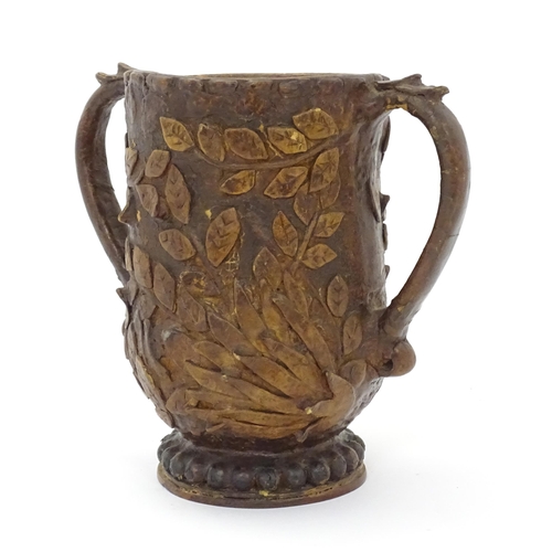 1260 - An Arts & Crafts leather and papier mache twin handled vase with wooden base and  foliate decoration... 