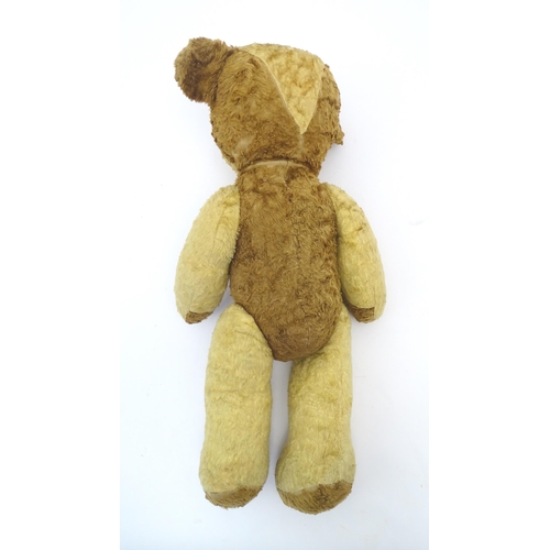 1433 - Toy: A 20thC straw filled teddy bear with leather tongue and articulated limbs. Approx. 22 1/2