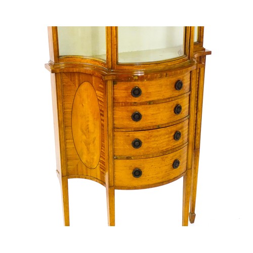 1629 - A 20thC display cabinet in the Sheraton style, having satinwood veneers over a serpentine shaped str... 