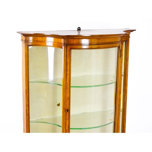 1629 - A 20thC display cabinet in the Sheraton style, having satinwood veneers over a serpentine shaped str... 