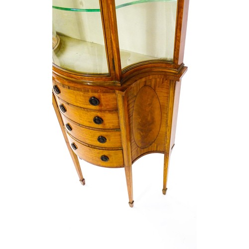 1629 - A 20thC display cabinet in the Sheraton style, having satinwood veneers over a serpentine shaped str... 