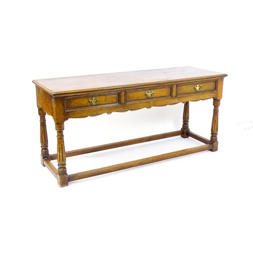 1644 - A mid 20thC oak dresser base with a moulded rectangular top above three short drawers with brass han... 