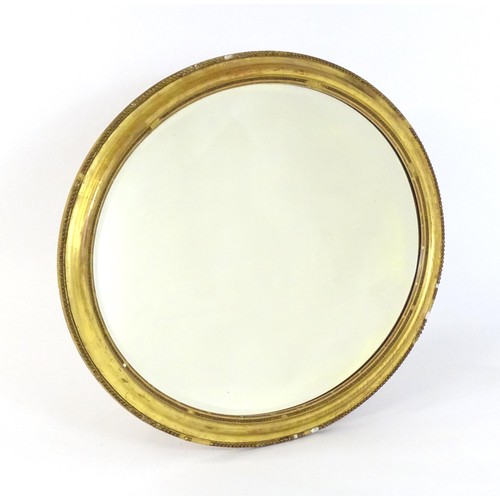 1658 - A 19thC oval giltwood and gesso wall mirror with bevelled glass. The surround having moulded and bea... 