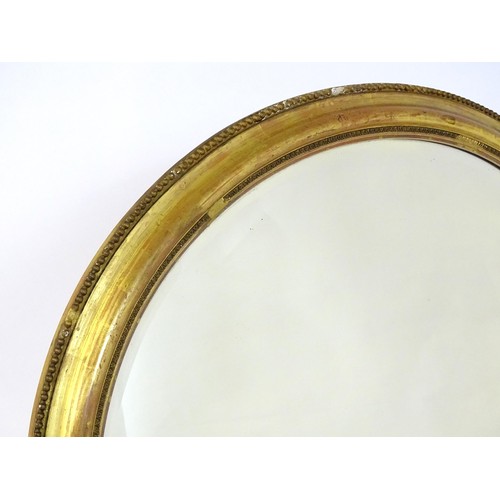 1658 - A 19thC oval giltwood and gesso wall mirror with bevelled glass. The surround having moulded and bea... 