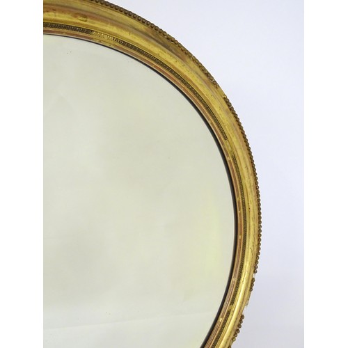 1658 - A 19thC oval giltwood and gesso wall mirror with bevelled glass. The surround having moulded and bea... 