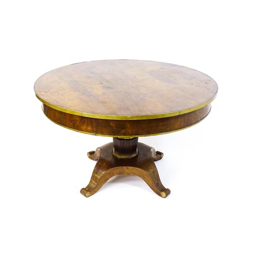 1671 - A 19thC mahogany breakfast table with a circular top and brass rim, the table having a canted pedest... 