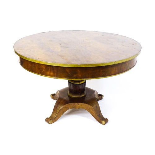 1671 - A 19thC mahogany breakfast table with a circular top and brass rim, the table having a canted pedest... 