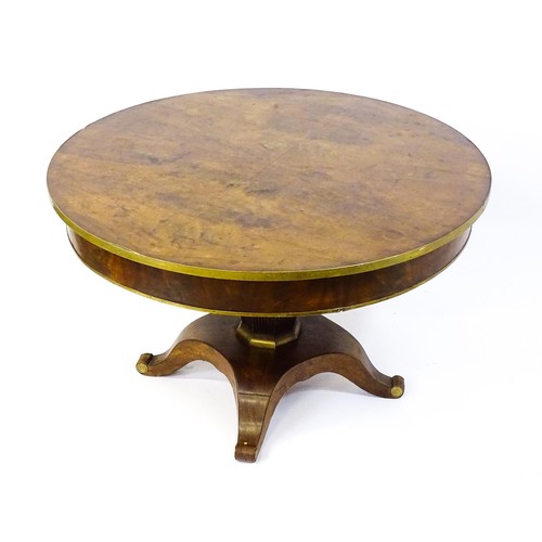 1671 - A 19thC mahogany breakfast table with a circular top and brass rim, the table having a canted pedest... 