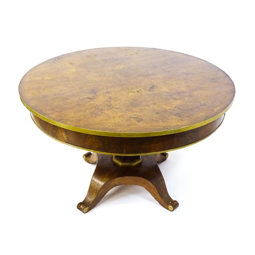 1671 - A 19thC mahogany breakfast table with a circular top and brass rim, the table having a canted pedest... 