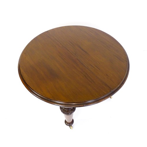 1677 - A Victorian mahogany dining table of circular form, extending to form an oval, the table raised on f... 