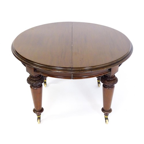 1677 - A Victorian mahogany dining table of circular form, extending to form an oval, the table raised on f... 