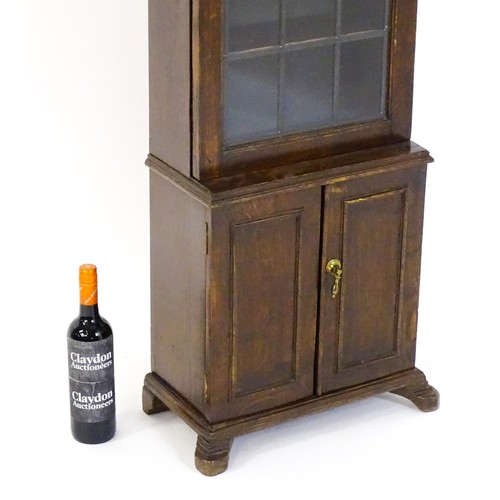 1681 - A 20thC oak cabinet of small proportions, with a moulded cornice above a glazed door and cupboard be... 