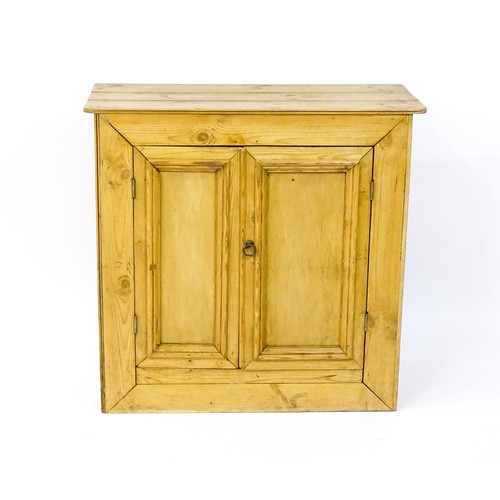 1697 - A 20thC pine cupboard with an overhanging plank top above two panelled doors. 36