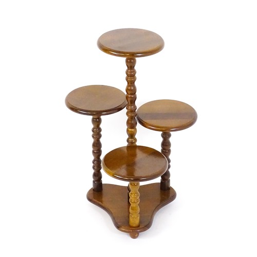 1707 - A 20thC hardwood plant stand with four graduated circular tiers raised on bobbin turned style suppor... 