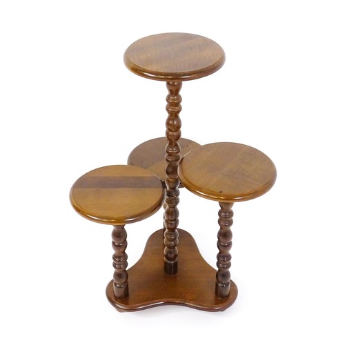 1707 - A 20thC hardwood plant stand with four graduated circular tiers raised on bobbin turned style suppor... 