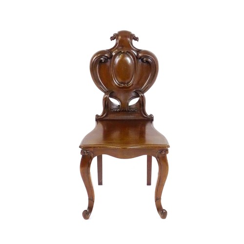 1715 - A mid 19thC mahogany hall chair, with a shaped backrest, scrolling motifs and acanthus carving, the ... 