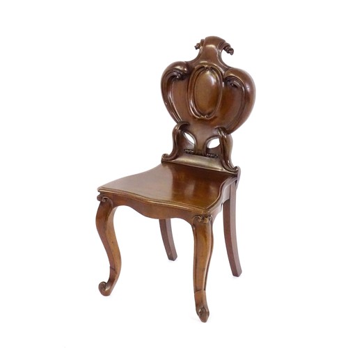 1715 - A mid 19thC mahogany hall chair, with a shaped backrest, scrolling motifs and acanthus carving, the ... 