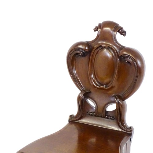 1715 - A mid 19thC mahogany hall chair, with a shaped backrest, scrolling motifs and acanthus carving, the ... 