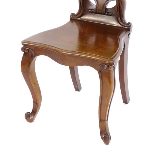 1715 - A mid 19thC mahogany hall chair, with a shaped backrest, scrolling motifs and acanthus carving, the ... 