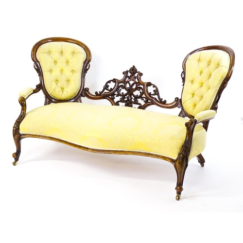 1718 - A late 19thC / early 20thC conversation sofa, with deep buttoned backrests separated by a carved, pi... 