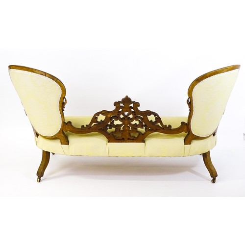 1718 - A late 19thC / early 20thC conversation sofa, with deep buttoned backrests separated by a carved, pi... 