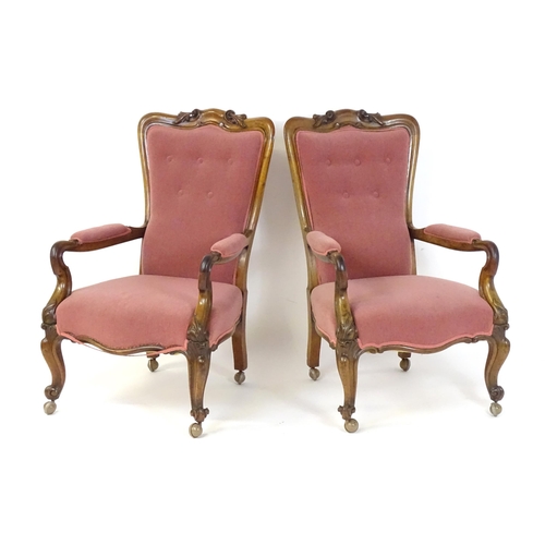 1719 - A pair of 19thC rosewood library chairs with carved cresting rails above buttoned backrests and carv... 