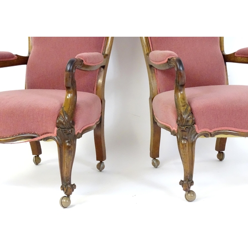 1719 - A pair of 19thC rosewood library chairs with carved cresting rails above buttoned backrests and carv... 