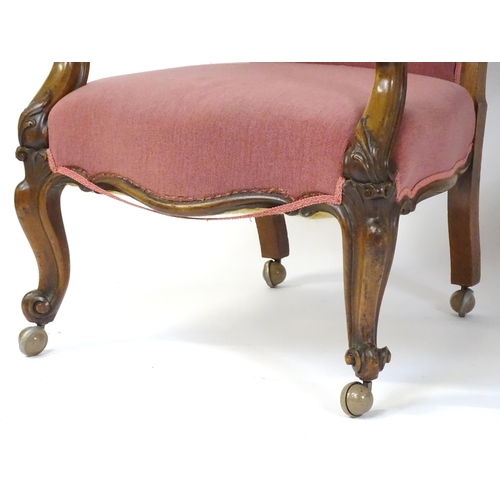 1719 - A pair of 19thC rosewood library chairs with carved cresting rails above buttoned backrests and carv... 