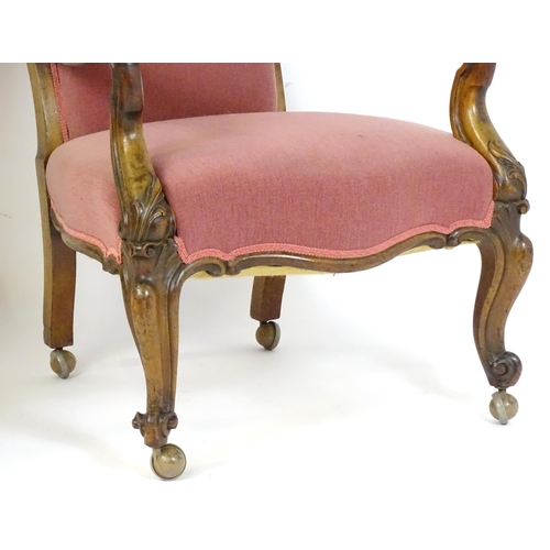 1719 - A pair of 19thC rosewood library chairs with carved cresting rails above buttoned backrests and carv... 