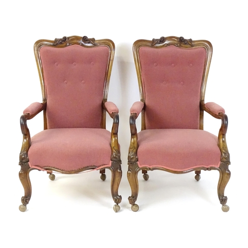 1719 - A pair of 19thC rosewood library chairs with carved cresting rails above buttoned backrests and carv... 